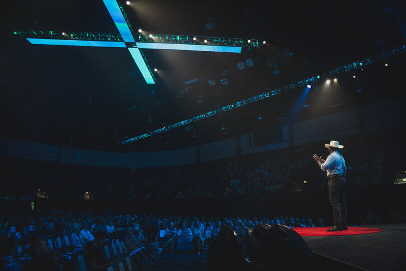 a speaker stands on stage at TEDxFargo